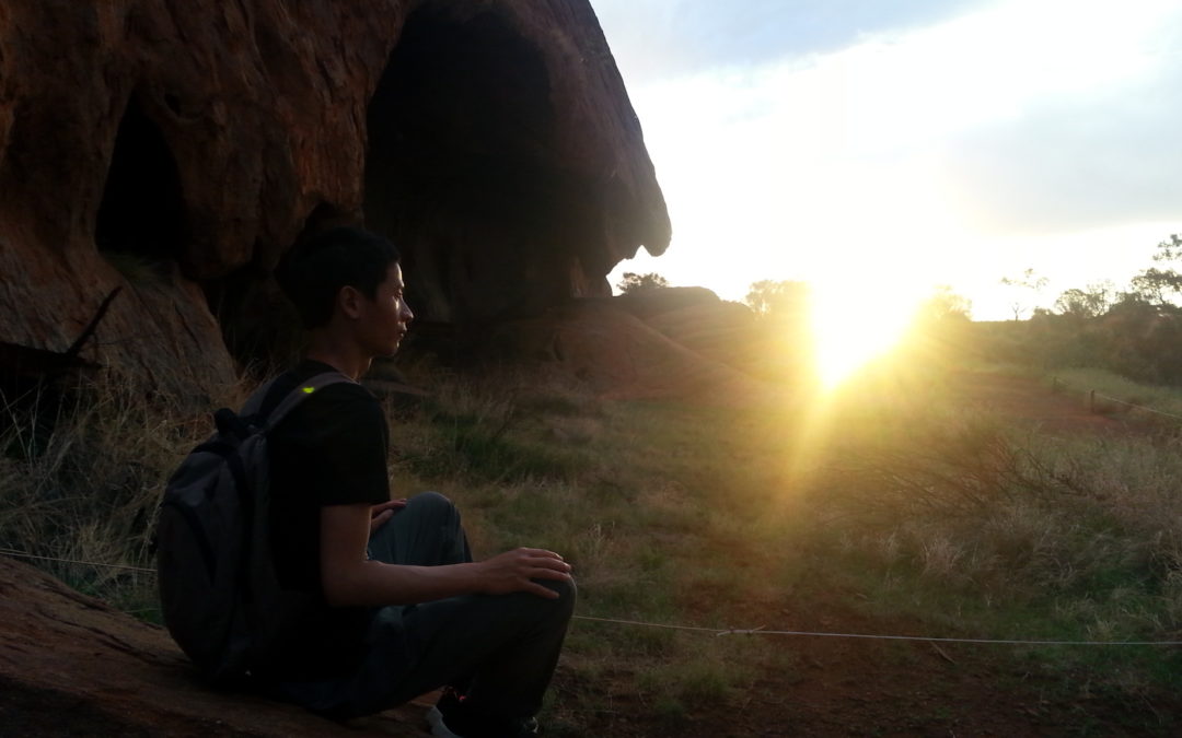 tim chan sitting and meditating on rock in uluru