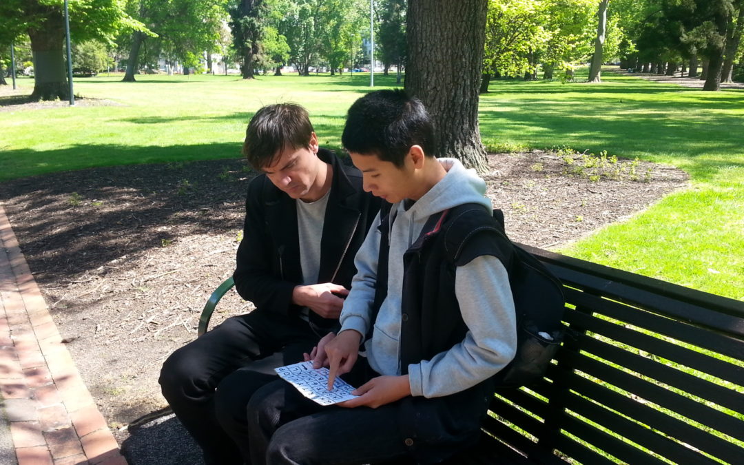 tim chan sitting on a park bench with support worker ruben